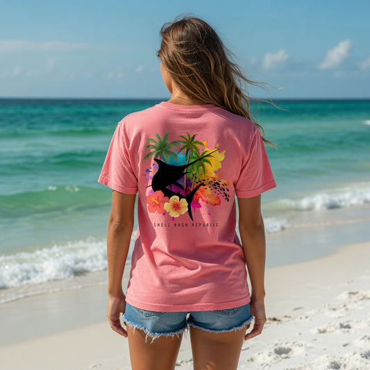 Woman from behind wearing a Shell Hash Republic Comfort Colors T-Shirt with a Marlin Splash Tropical Back Print, standing on a beach