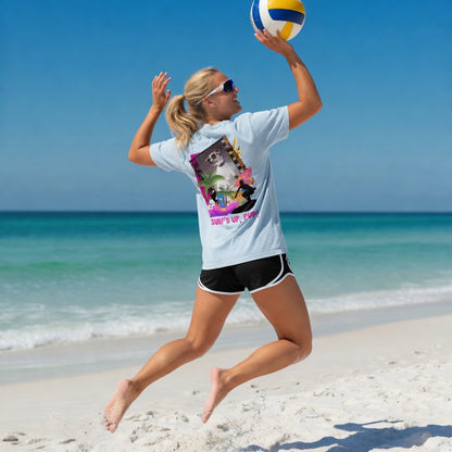 Woman jumping on a beach, wearing a Shell Hash Republic Comfort Colors T-Shirt with a Surfs Up Pup graphic on the back, playing volleyball