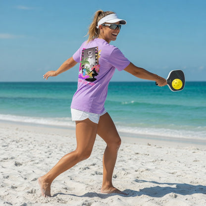 Woman playing pickleball on the beach wearing a Shell Hash Republic Comfort Colors T-Shirt with a Surf's Up Pup graphic
