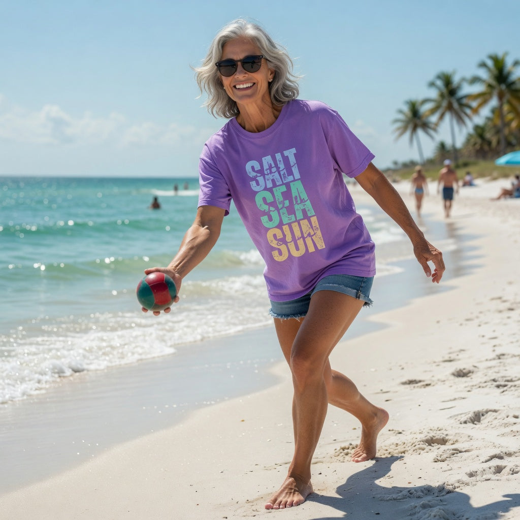 Woman in Shell Hash Republic Neon Comfort Colors T-Shirt with Salt Sea Sun graphic playing bocce ball on a beach