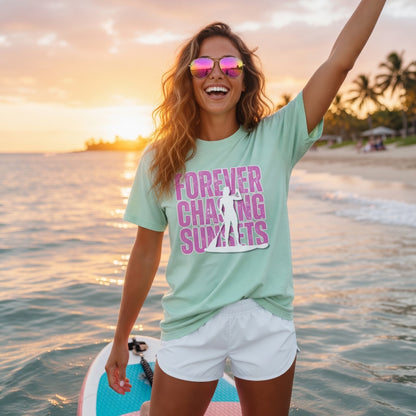 Shell Hash Republic Neon Comfort Colors T-Shirt with Forever Chasing Sunsets graphic, worn by a woman on a paddleboard at sunset