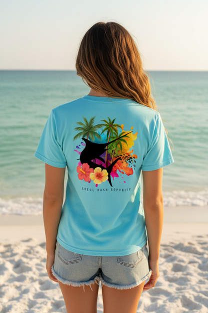 Woman from behind wearing a Shell Hash Republic Comfort Colors T-Shirt with a Marlin Splash Tropical Back Print, standing on a beach facing the ocean