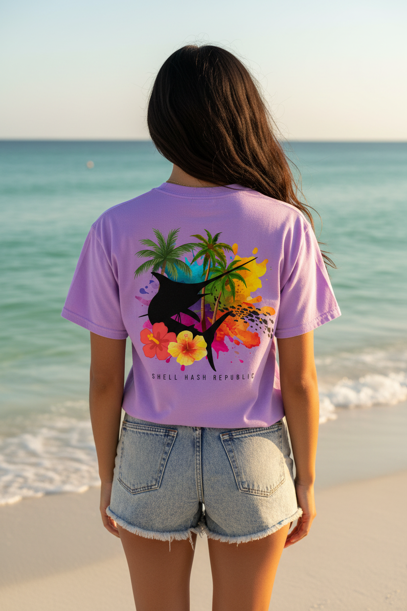 Woman in Shell Hash Republic Comfort Colors T-Shirt with Marlin Splash Tropical Back Print, Swordfish Splash Collage, on a beach