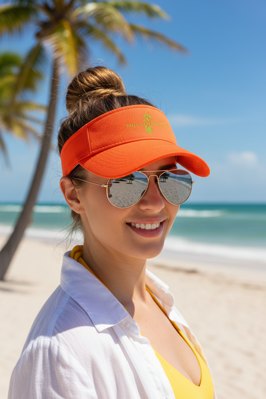 Woman wearing a Shell Hash Republic Sport-Tek RacerMesh Visor in Neon Orange, sunglasses, and a white shirt on a beach with palm trees
